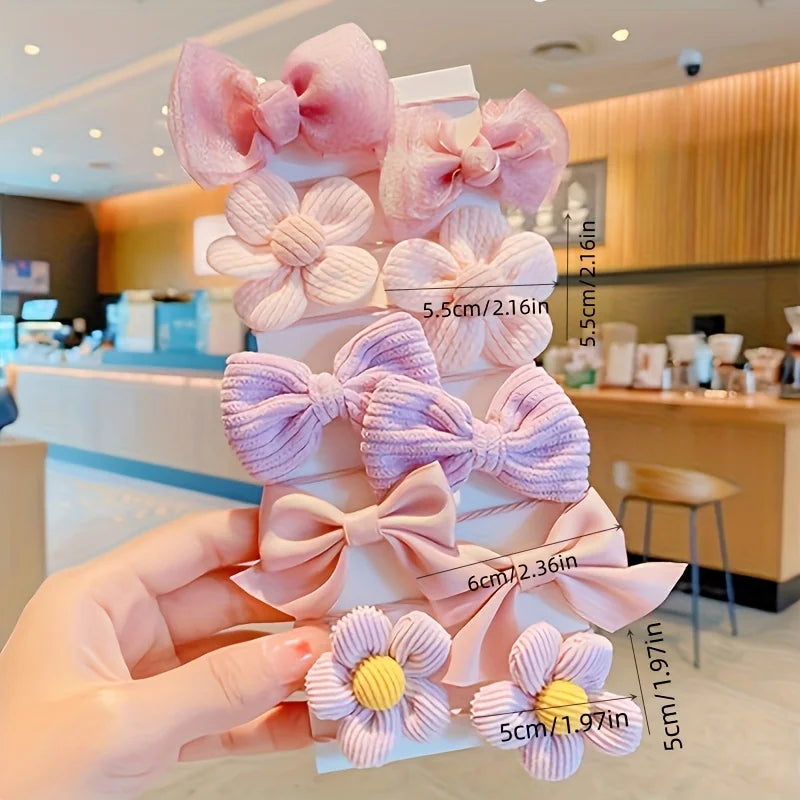 Hand holding a set of kawaii pastel pink and purple hair clips with bows and flower designs, KawaiiLands style.